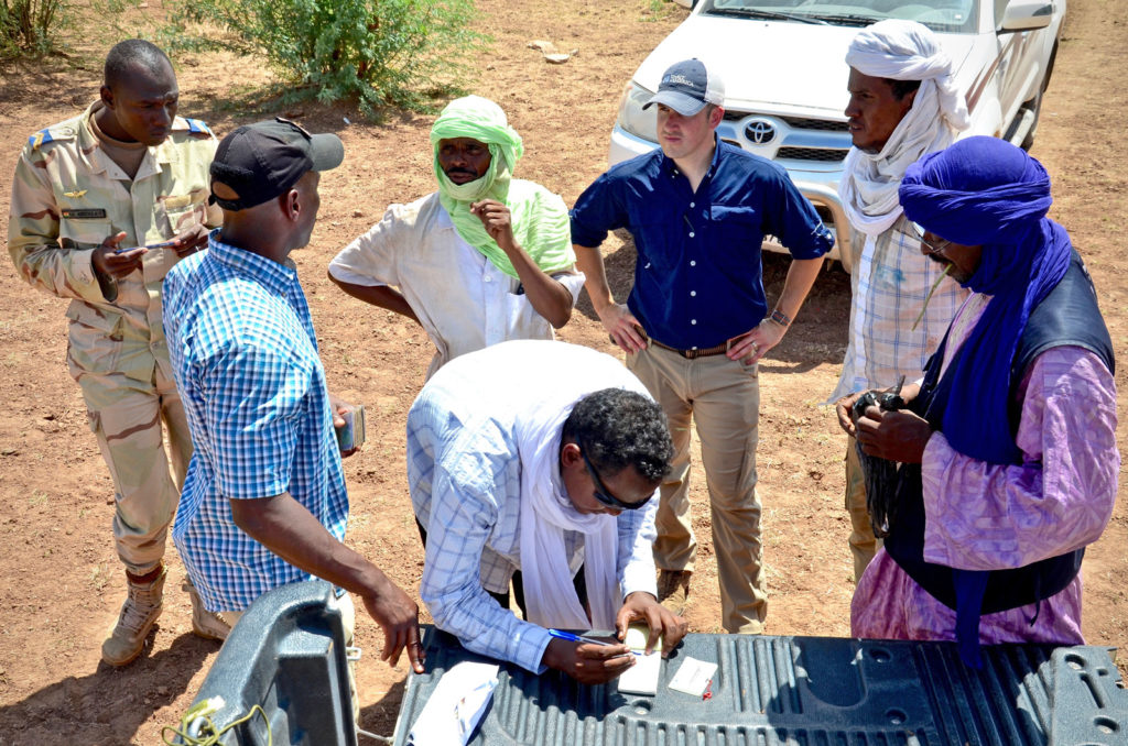 SoA Field Rep, Chris, and the US Army Team leader coordinate with a vaccination team and their security escorts in the field outside of Ingall, Niger