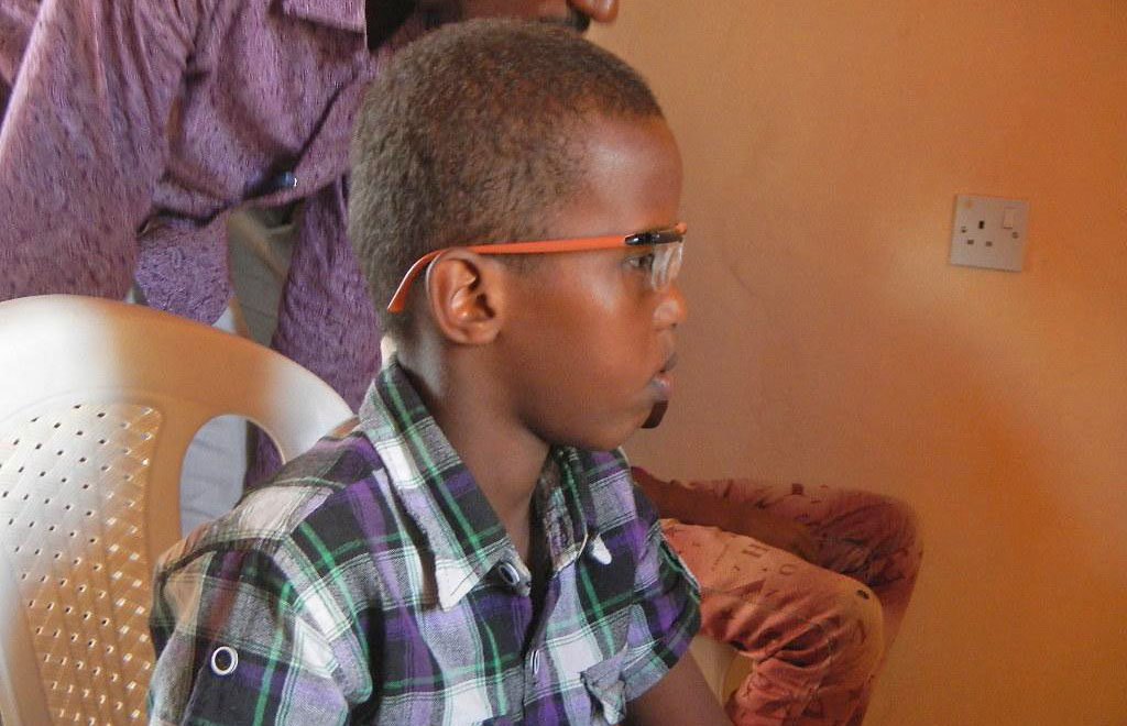 A local medical provider helps a young orphan adjust his new glasses during a recent US outreach event in East Africa.