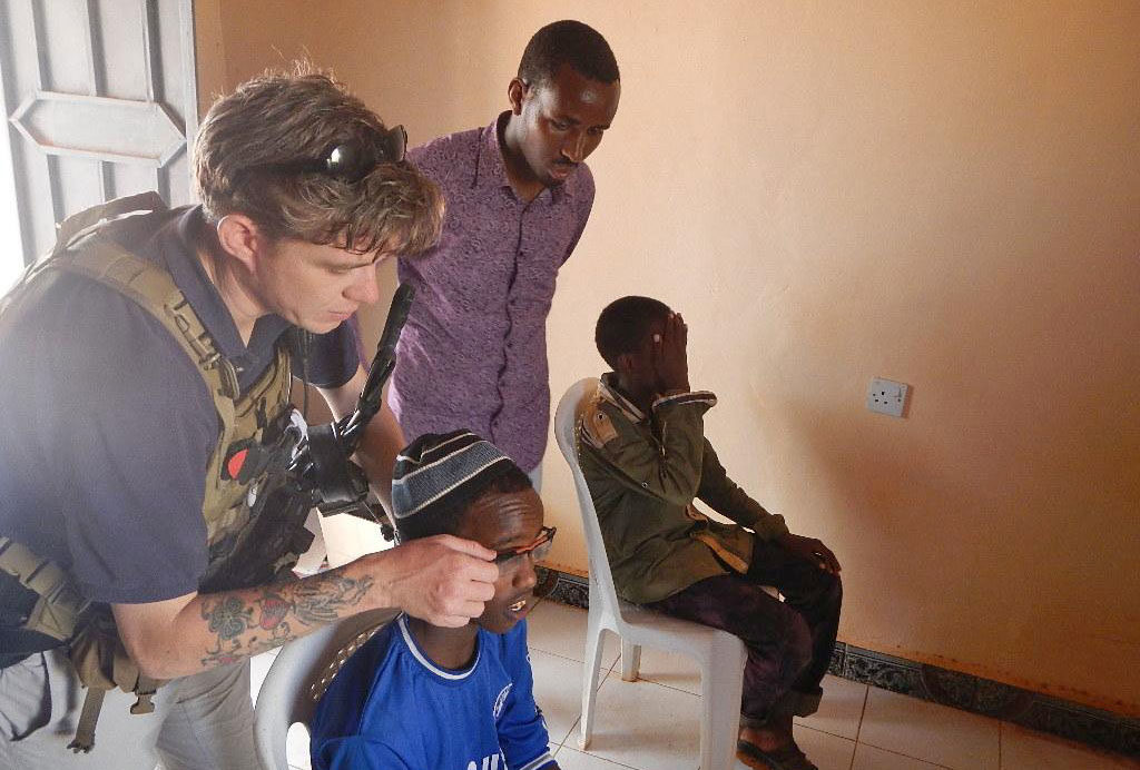 A US Civil Affairs sergeant adjusts the prescription on a pair of Adlens glasses for a young local boy during a recent outreach event.