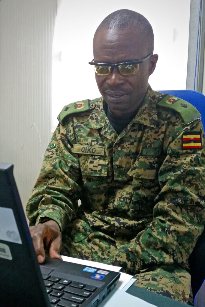 Colonel Oiko, wearing adjustable Adlens glasses, works on his laptop. Previously, his vision was so poor that he couldn’t read his computer screen